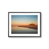 Framed photograph of a coastal scene with a sunset over a body of water.
