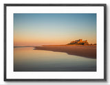 Bamburgh Castle at sunrise reflecting on wet sand, Northumberland coast