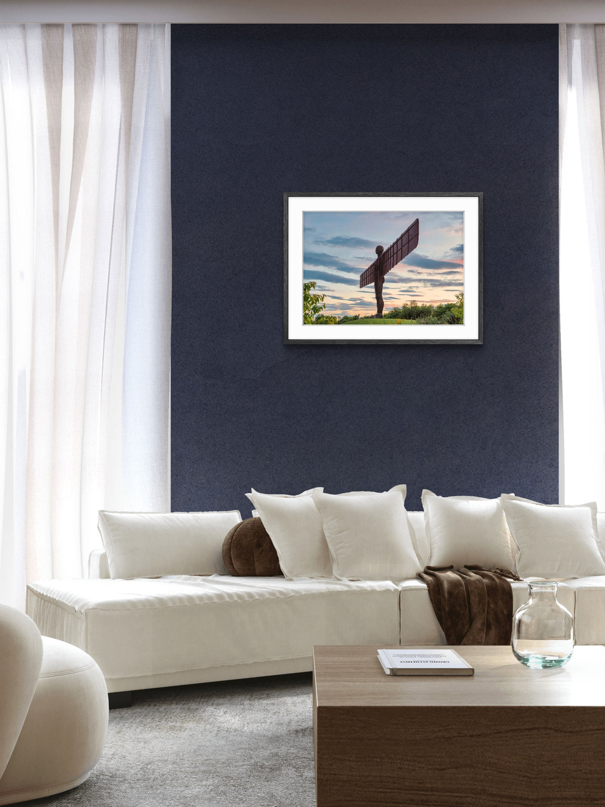 Framed Angel of the North print displayed on a dark navy wall above a white sofa in a modern living room.