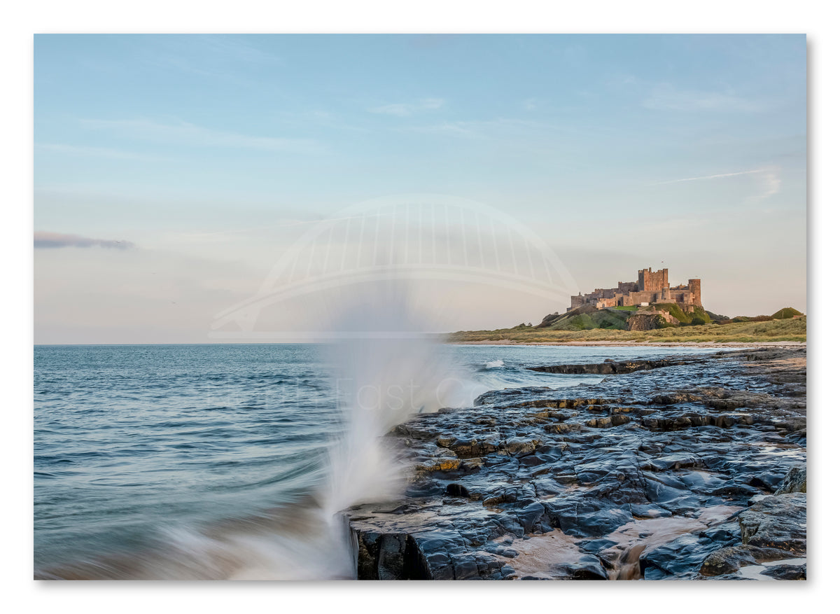 Waves crashing on rocks below Bamburgh Castle shown as a canvas print.