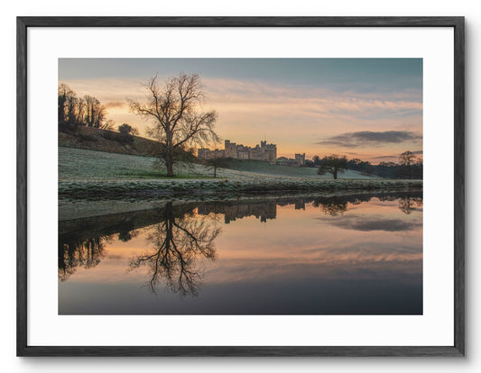 Framed print of Alnwick Castle reflected in the River Aln in Northumberland.