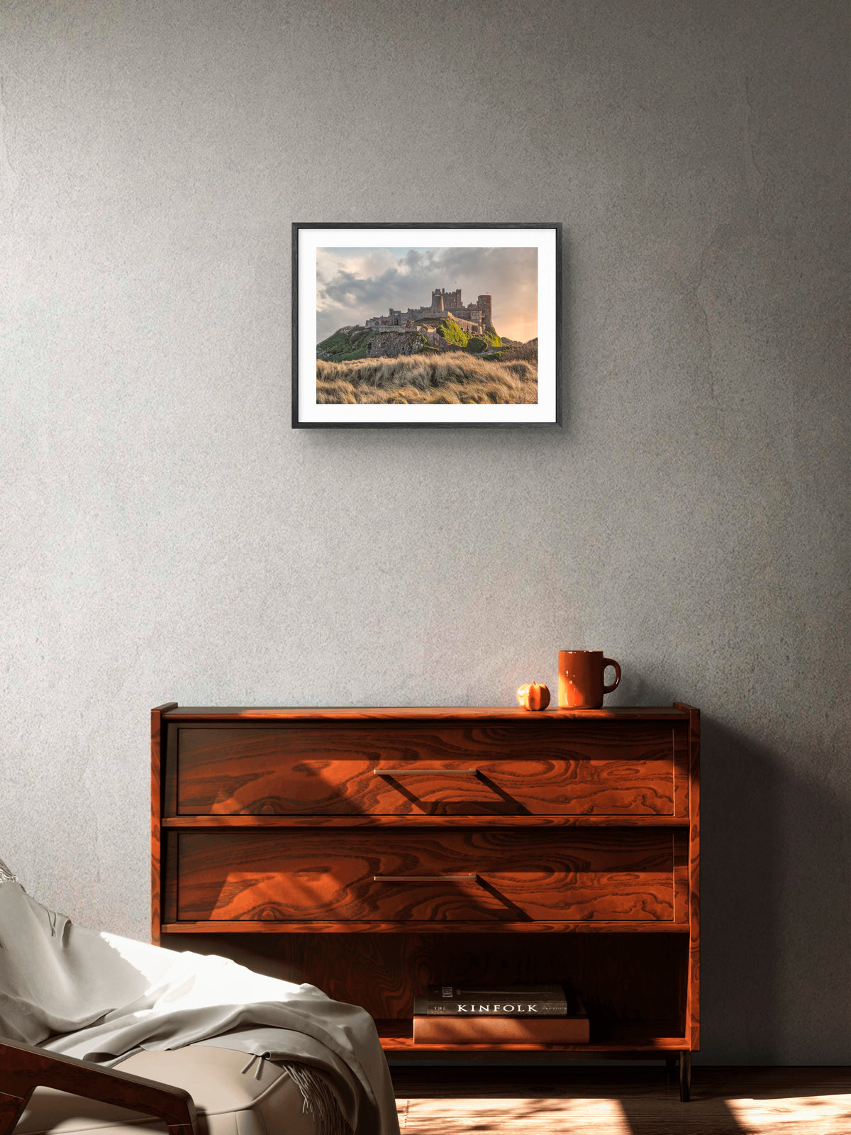 Bamburgh Castle beyond grass-covered dunes wall art displayed in a styled room setting.