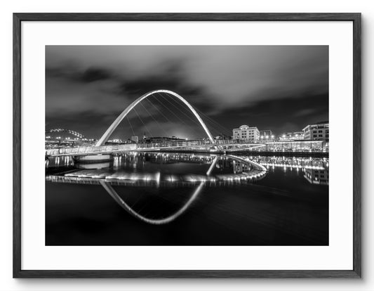 Millennium Bridge Gateshead Reflecting on The Tyne - Black and White shown as a framed photographic print.