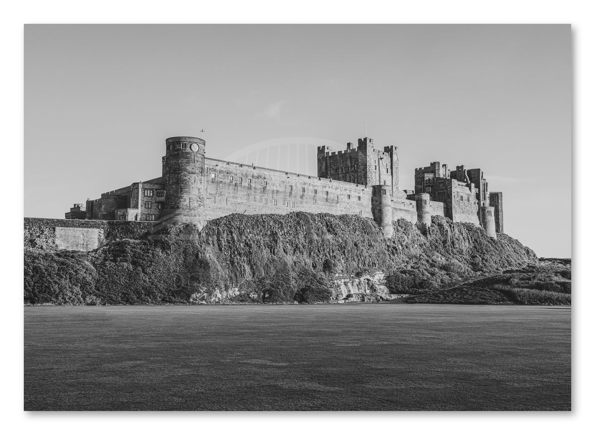 Black-and-white Bamburgh Castle from the cricket field shown as a canvas print.