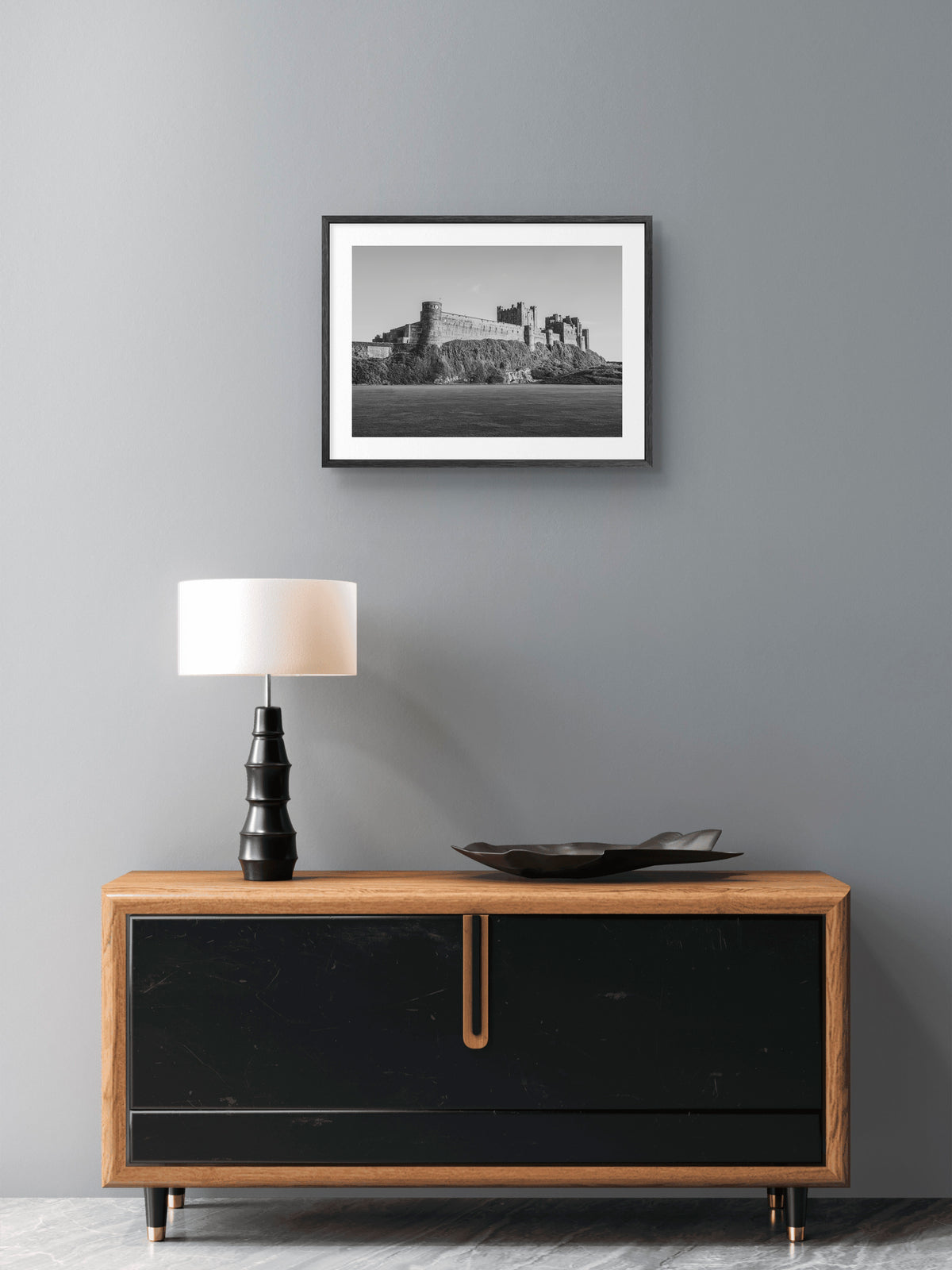 Black-and-white Bamburgh Castle from the cricket field wall art displayed in a styled room setting.
