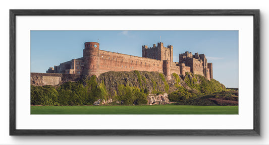 Bamburgh Castle in Golden Light panoramic print — black frame and white mount