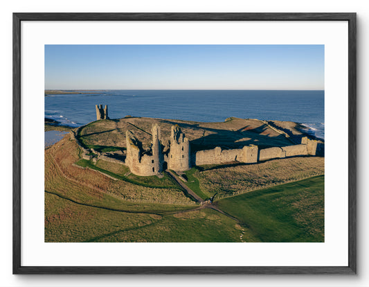 Aerial view of Dunstanburgh Castle shown as a framed photographic print.
