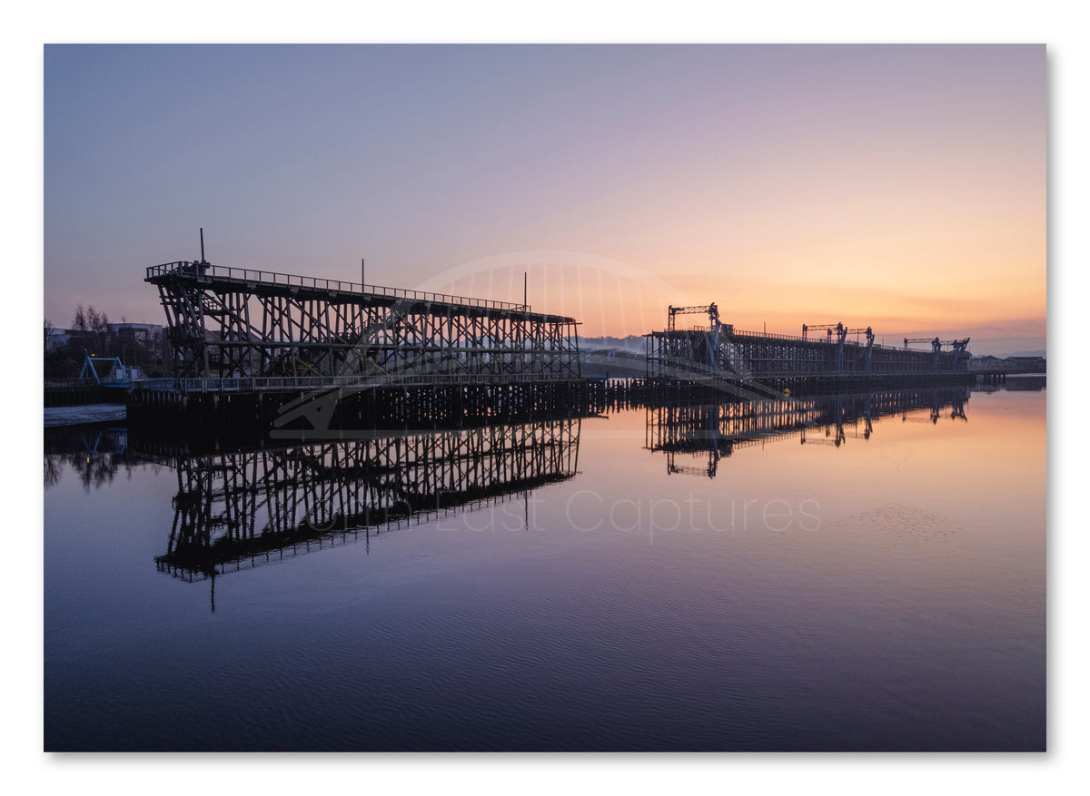 Dunston Staiths reflected in the River Tyne at sunset shown as a canvas print.