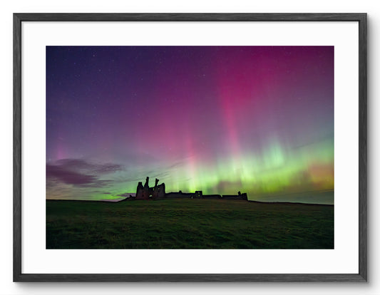 Northern Lights above Dunstanburgh Castle shown as a framed photographic print.