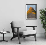 Gray armchair in a room with a framed picture of a mountain landscape on the wall.