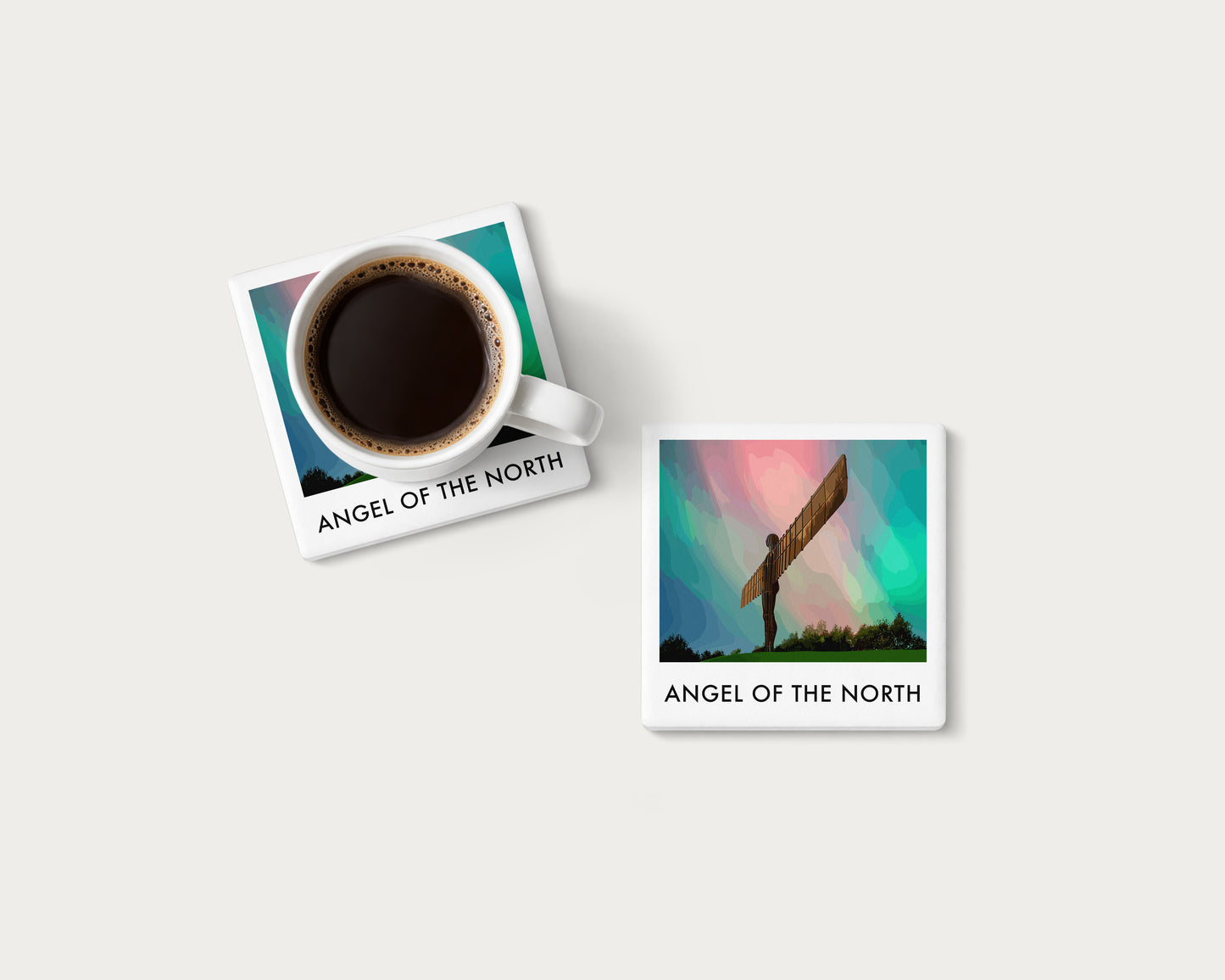 Illustrated ceramic coaster showing the Angel of the North beneath colourful aurora; mockup with a coffee mug.
