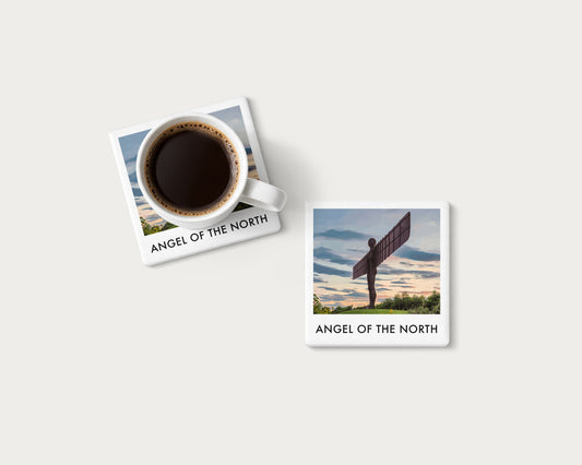 Illustrated ceramic coaster showing the Angel of the North against a warm sunset; mockup with a coffee mug.