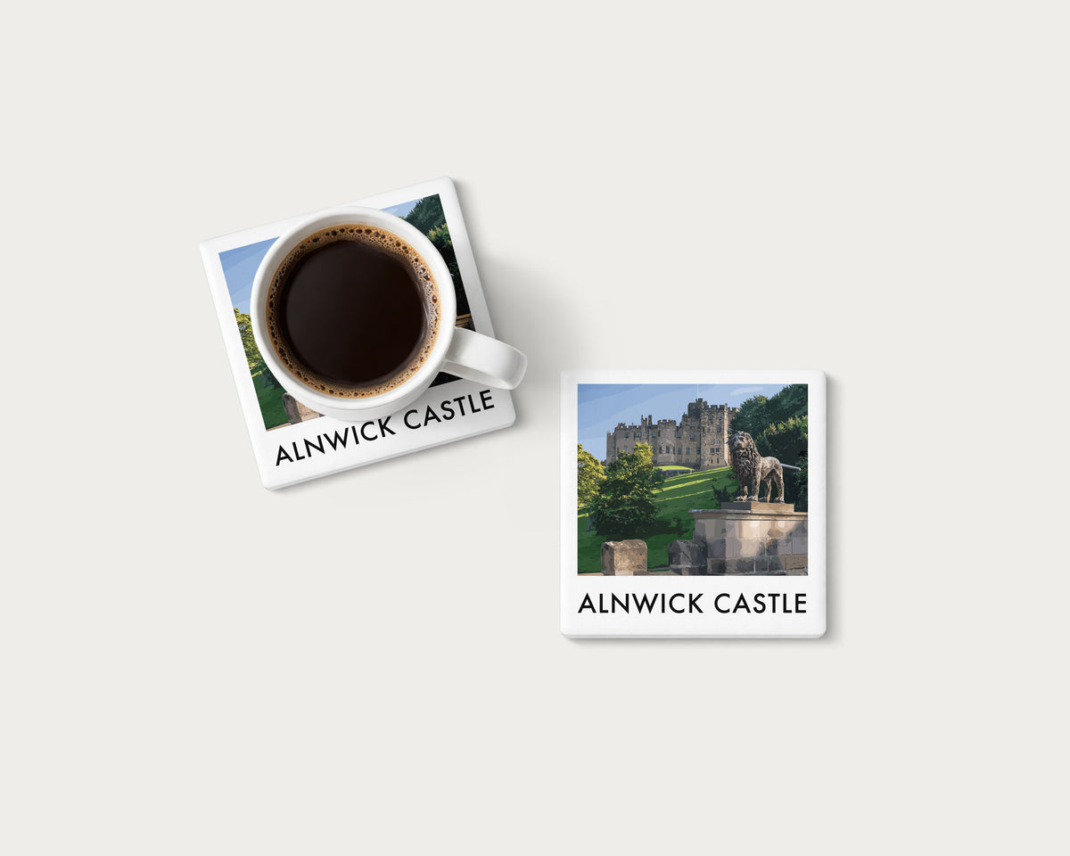 Illustrated ceramic coaster showing Alnwick Castle in an illustrated landscape; mockup with a coffee mug.