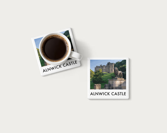 Illustrated ceramic coaster showing Alnwick Castle in an illustrated landscape; mockup with a coffee mug.