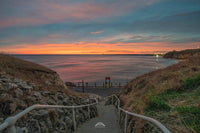 Pathway leading to a beach with a sunset over the ocean