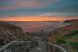 Pathway leading to a beach with a sunset over the ocean