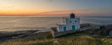 Lighthouse on a coastal landscape during sunset