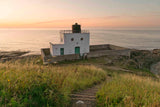 Lighthouse on a cliff overlooking the ocean at sunset