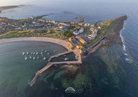 Aerial view of a coastal town with a pier and boats in a harbor.