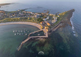 Aerial view of a coastal town with a pier and boats in a harbor.