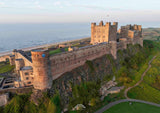 Aerial view of a large castle with a coastal background