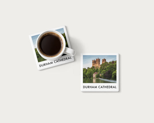Illustrated ceramic coaster showing Durham Cathedral above trees and the River Wear; mockup with a coffee mug.
