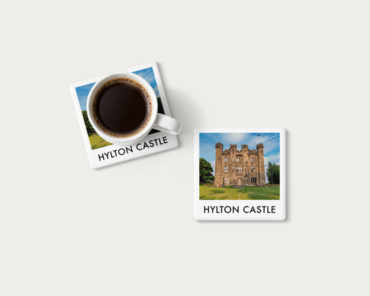 Illustrated ceramic coaster showing Hylton Castle across a green lawn beneath blue sky; mockup with a coffee mug.