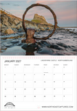 A January 2027 calendar page featuring a photograph of Lindisfarne Castle and rocky shoreline, with a large blurred ring in the foreground and a printed calendar grid below.