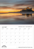 A single-page calendar spread showing a landscape photograph of Bamchurch Castle on a rocky island at sunset across calm water, with a July 2027 calendar grid below. The photo has warm golden and orange tones reflecting on the water, and the page includes a small logo and website text at the bottom.