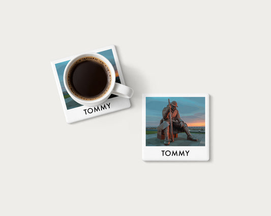 Illustrated ceramic coaster showing the Tommy statue in Seaham beneath a blue evening sky; mockup with a coffee mug.