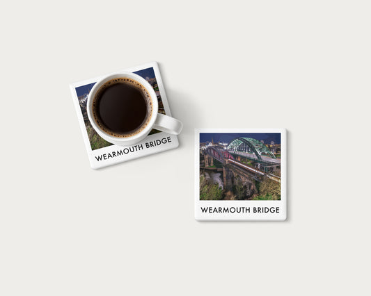 Illustrated ceramic coaster showing Wearmouth Bridge illuminated at night above the River Wear; mockup with a coffee mug.