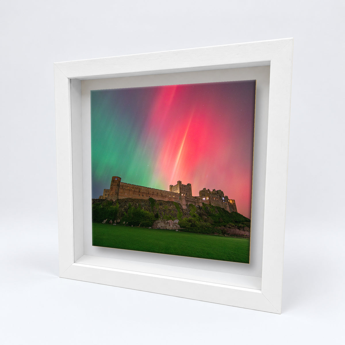 Bamburgh Castle Northern Lights on an 8×8 inch ceramic tile in a white box frame, angled view