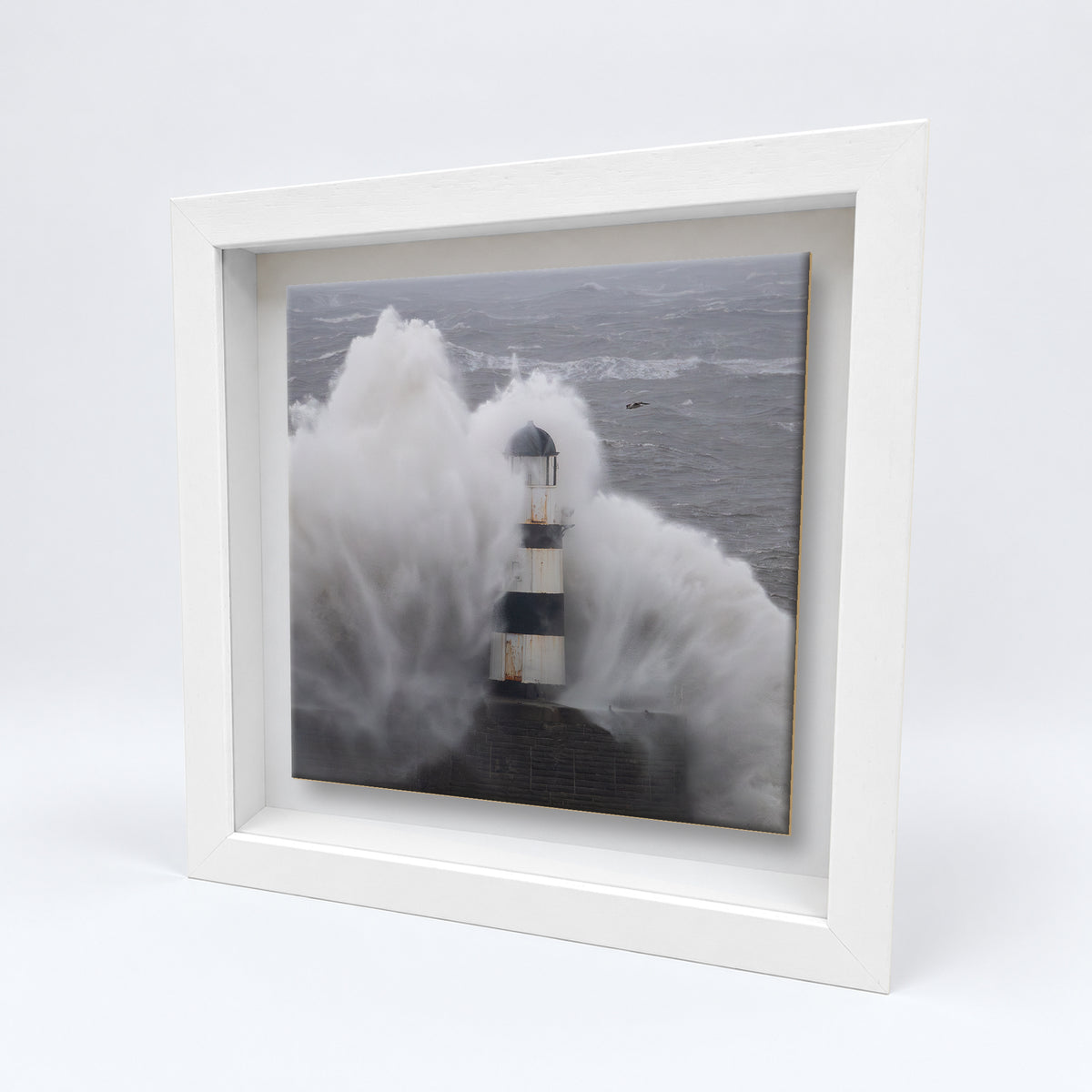Seaham Lighthouse Storm Babet on an 8×8 inch ceramic tile in a white box frame, angled view