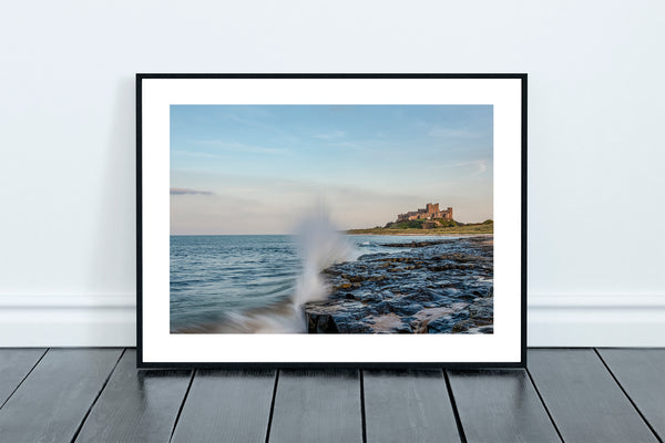 Bamburgh Castle and Beach at Sunset in Northumberland with waves crashing against the rocks at high tide. - North East Captures